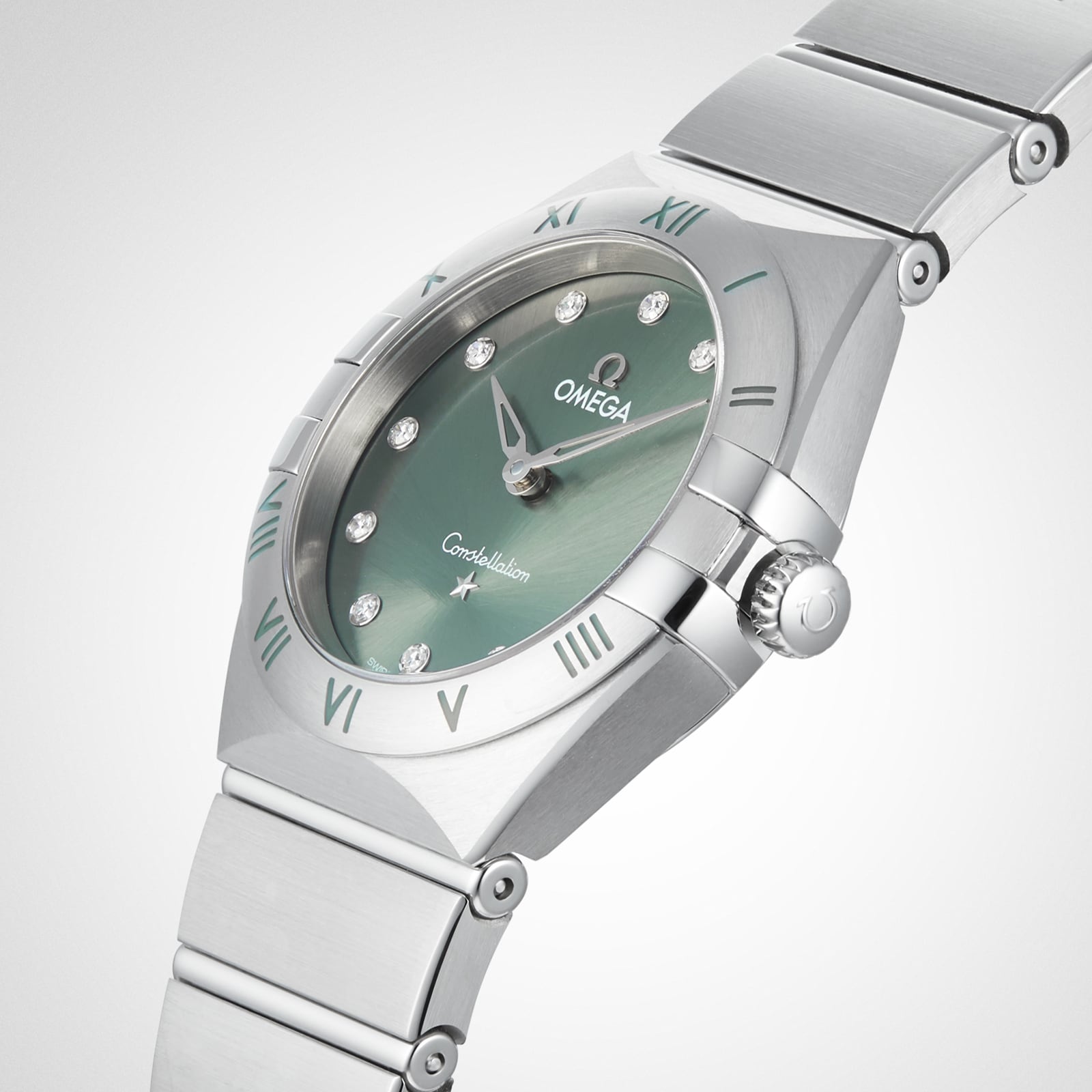 The OMEGA Constellation wristwatch features a stainless steel case, matcha green dial, diamond hour markers, Roman numerals on the bezel, and a metal bracelet, displayed at an angle on a white background.