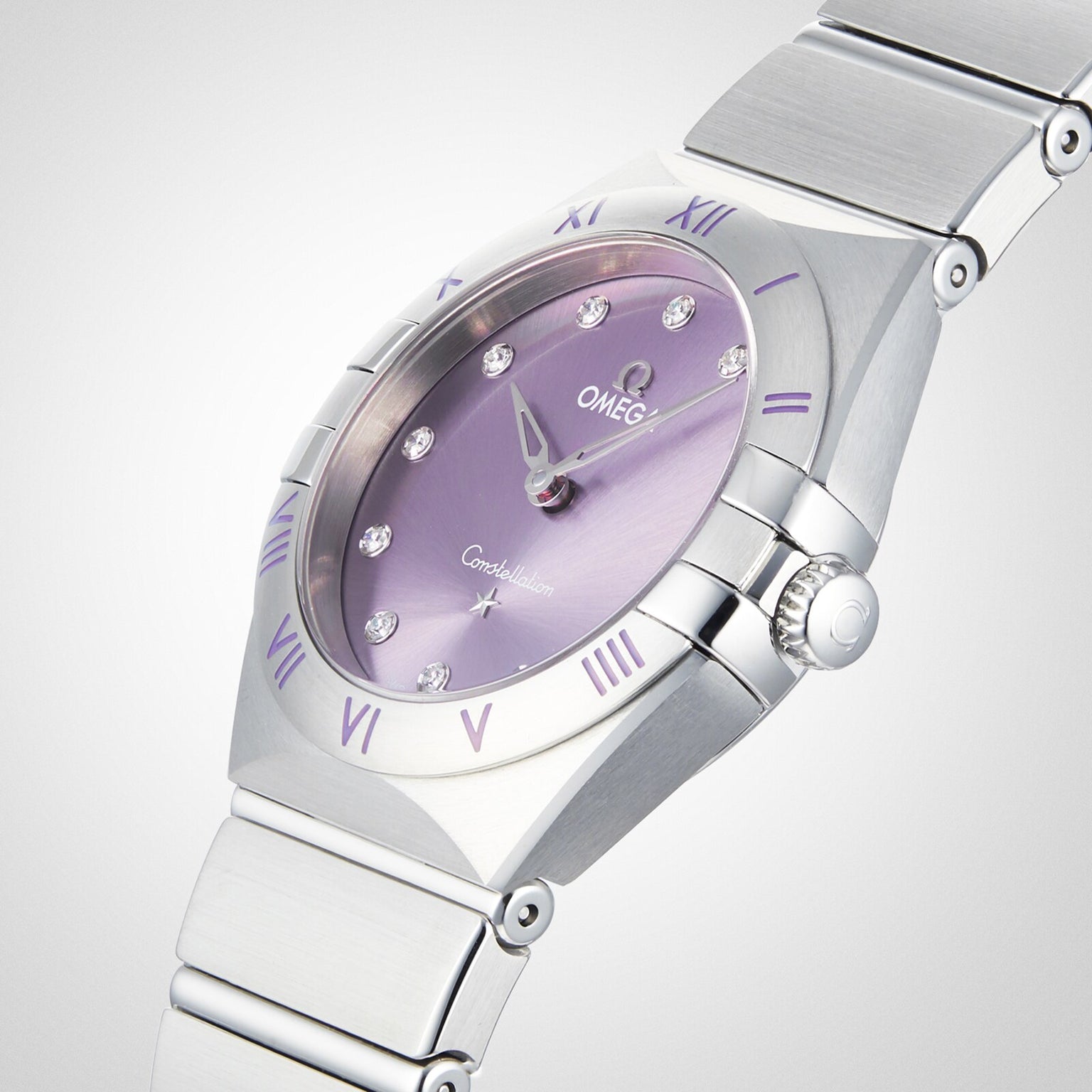 An OMEGA Constellation watch with a silver stainless steel bracelet, purple dial featuring diamond hour markers, and Roman numerals on the bezel is shown against a plain white background.
