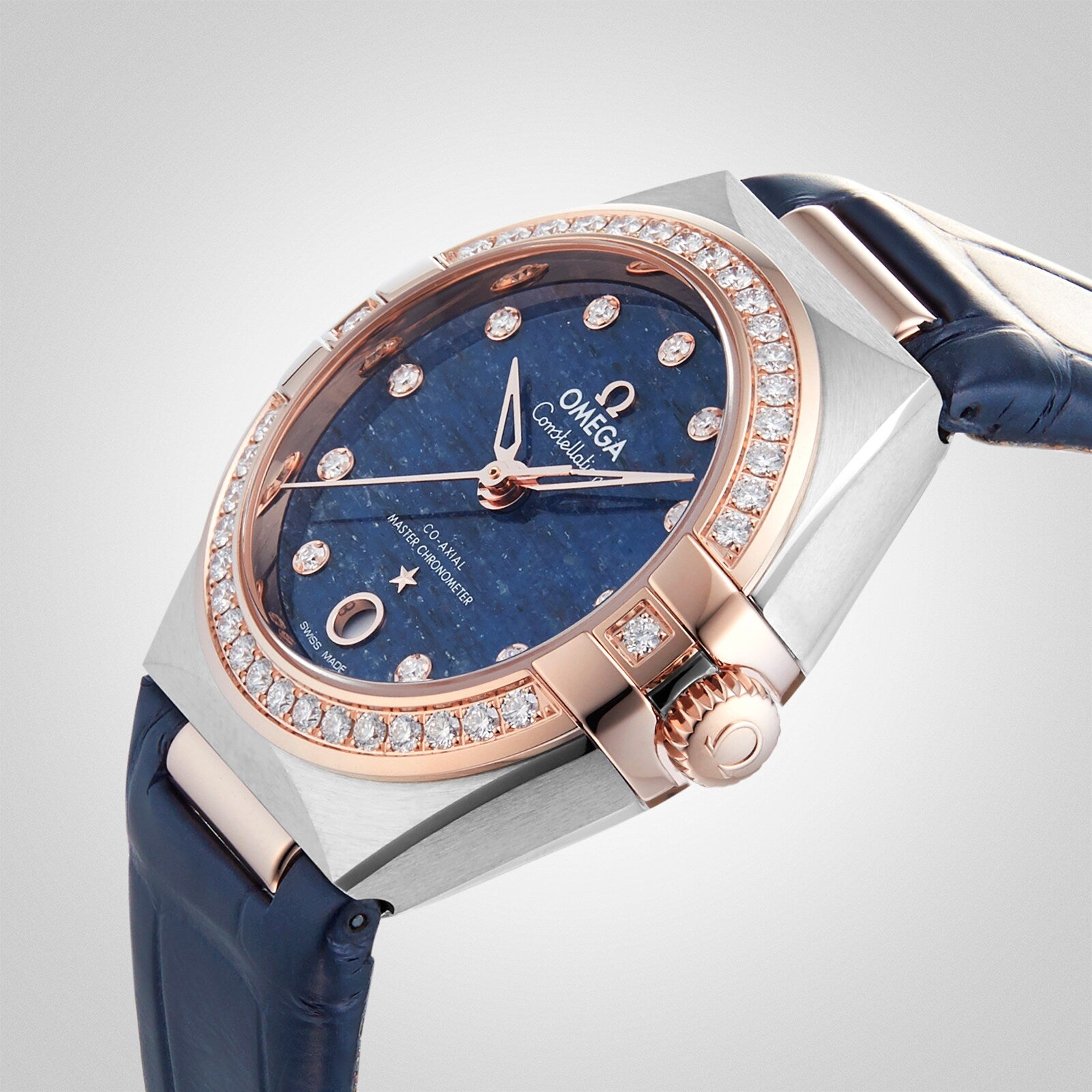 OMEGA Constellation features a blue dial with diamond hour markers, a diamond-set bezel, and a case in silver and 18K Sedna™ gold. Paired with a blue leather strap, it is an elegant addition to the OMEGA collection.