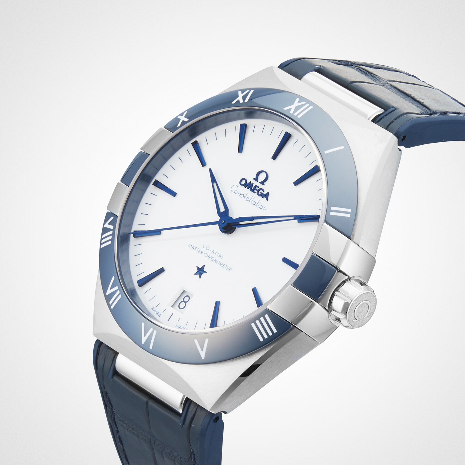 An OMEGA Constellation wristwatch features a white dial, Roman numeral markers, a blue bezel, stainless steel case, and blue leather strap. The watch is displayed against a plain white background.
