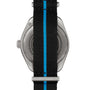 The image shows the back of an OMEGA Seamaster Planet Ocean 6000M dive watch with a black strap and a blue center stripe, highlighting its metal case and engraved details.