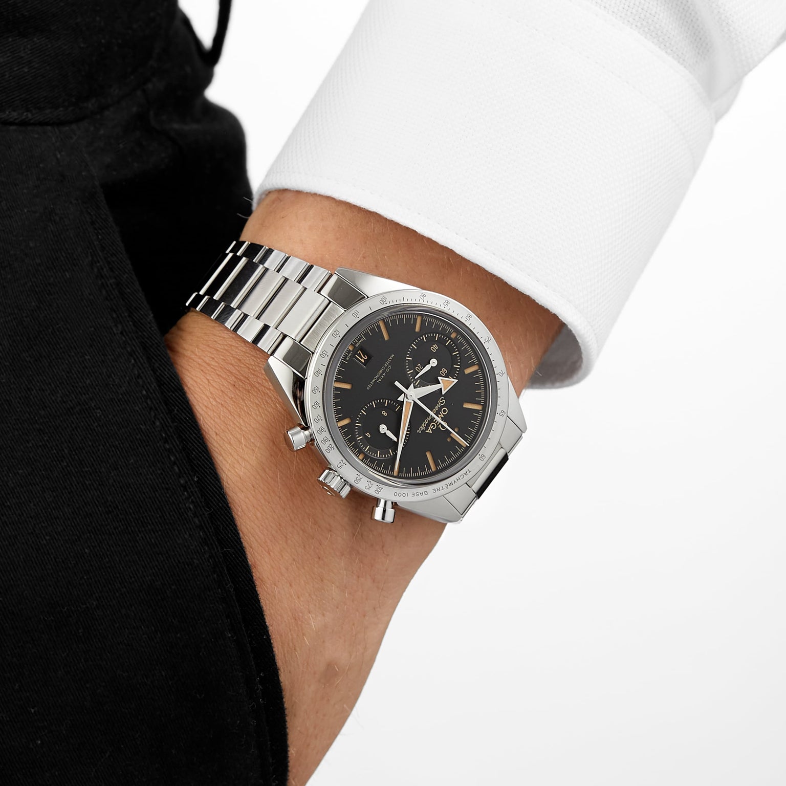 A person wearing the OMEGA Speedmaster 57 with a stainless steel case, black dial, and chronograph features casually slips their hand into a pocket.