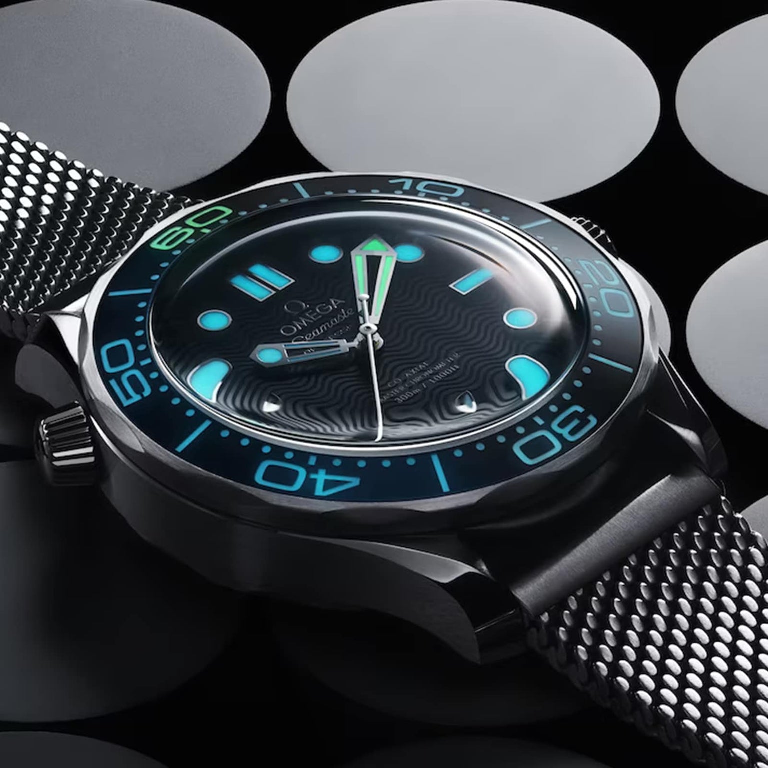 Close-up of an OMEGA Seamaster Diver 300M James Bond 007 60th Anniversary watch with glowing blue and green markers, set against a backdrop of large, overlapping gray and black circles.