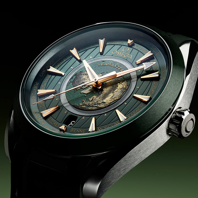 Close-up of the OMEGA Seamaster Aqua Terra 150M watch featuring a green dial, gold hands, central world map detail, and city names around the face.