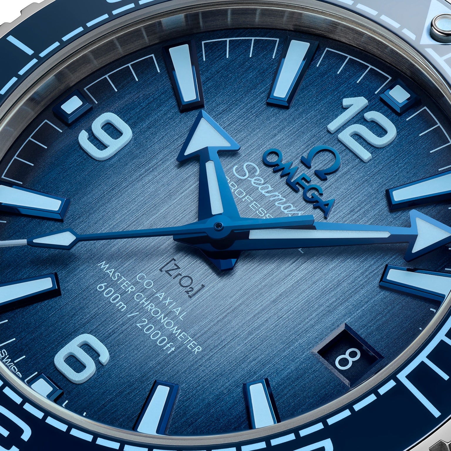 Close-up of the OMEGA Seamaster Planet Ocean 600M Summer Blue watch face, showing blue hands, bold numerals, a date window at 6 oclock, and a 600m/2000ft water resistance mark.