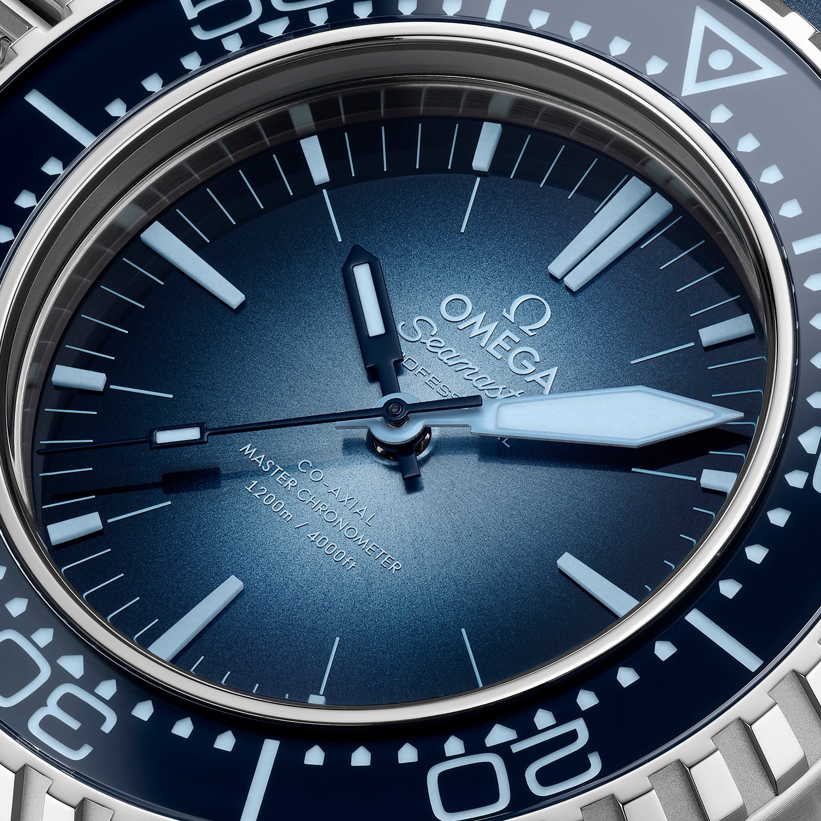 Close-up of an OMEGA Seamaster Ploprof 1200M Summer Blue dive watch, featuring a blue face, silver hands, white markers, and displaying the brand logo with Co-Axial Master Chronometer details on the dial.