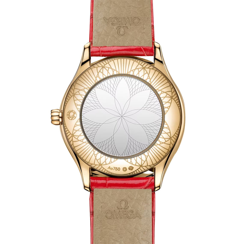 The De Ville Mini Trésor by OMEGA features an engraved geometric flower on the 18K Moonshine™ Gold caseback, complemented by a red leather strap.