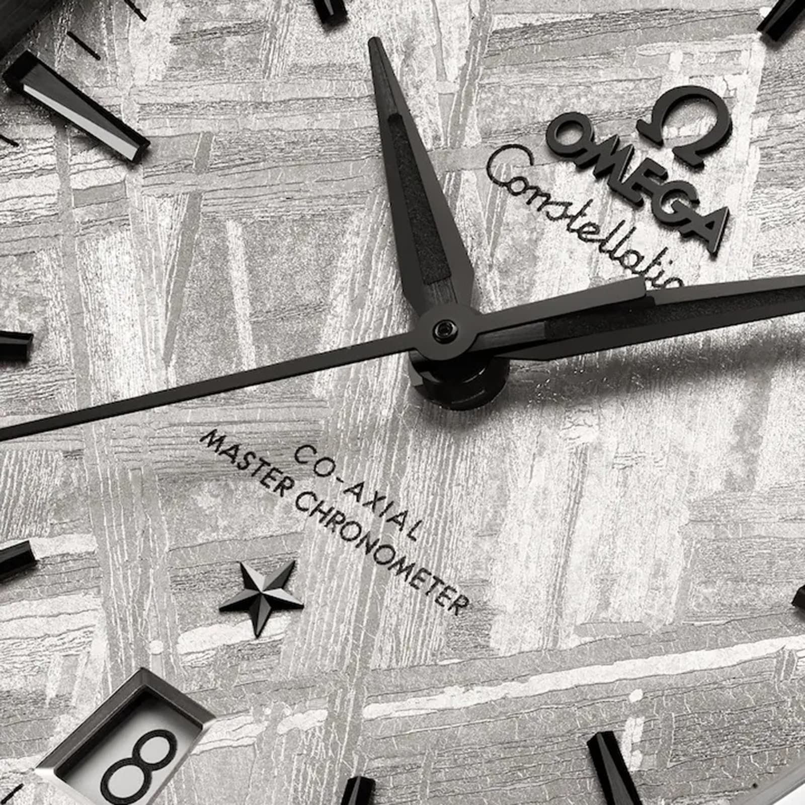 Close-up of an OMEGA Constellation watch face with black hands, meteorite dial, date window at 6 o’clock, and “Co-Axial Master Chronometer” text.