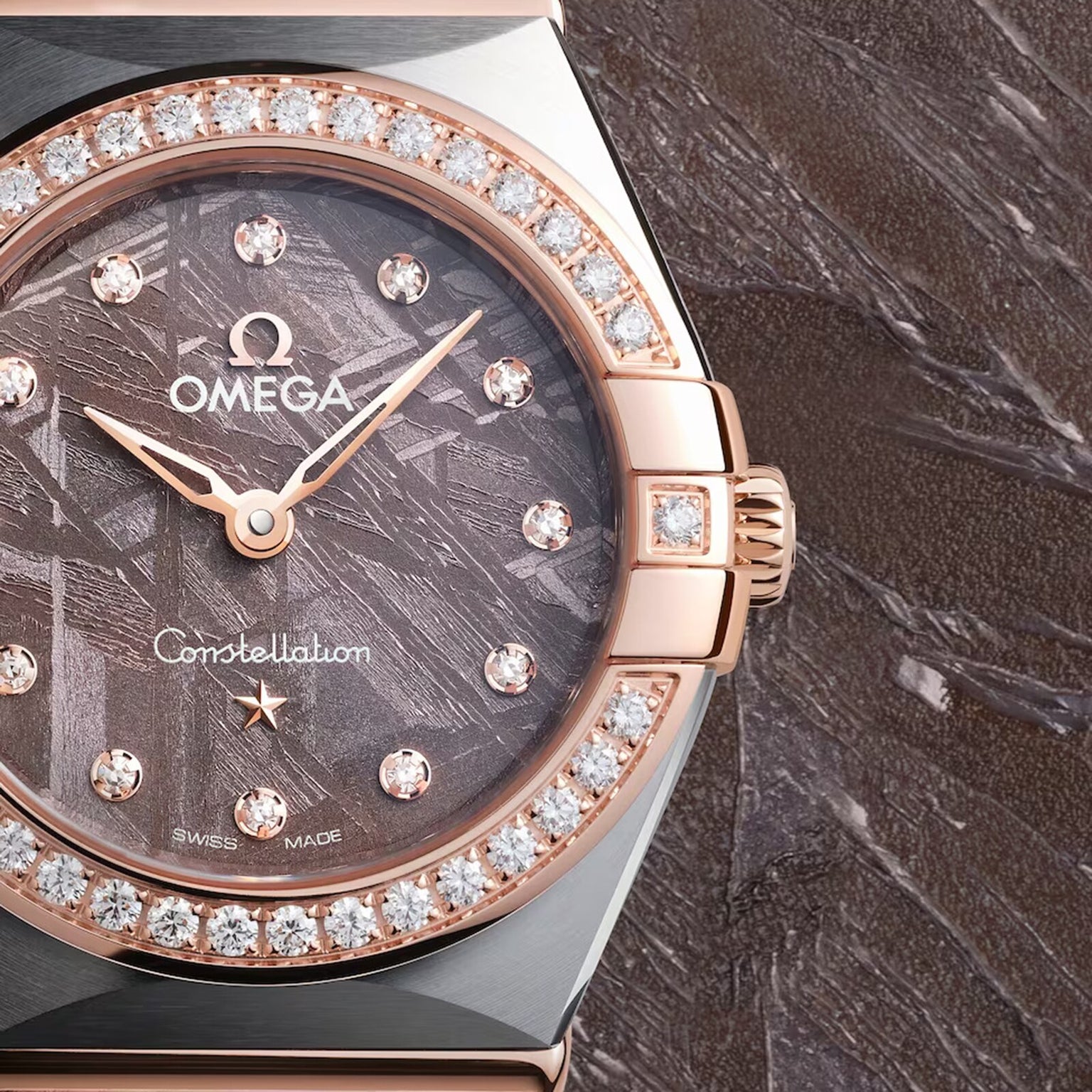Close-up of the OMEGA Constellation wristwatch with a diamond-set bezel, diamond hour markers, and a meteorite dial, shown against a coordinating textured backdrop.