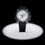 An OMEGA Speedmaster Moonwatch Professional with a stainless steel case, white dial, black bezel, and black rubber strap is showcased under a spotlight.