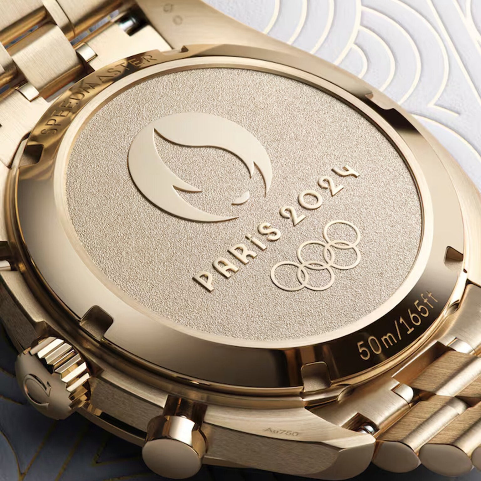 Close-up of the OMEGA Speedmaster Chronoscope Paris 2024 Olympics gold caseback, engraved with the Olympic Games Paris 2024 logo, Olympic rings, Master Chronometer certification, and 50m/165ft.