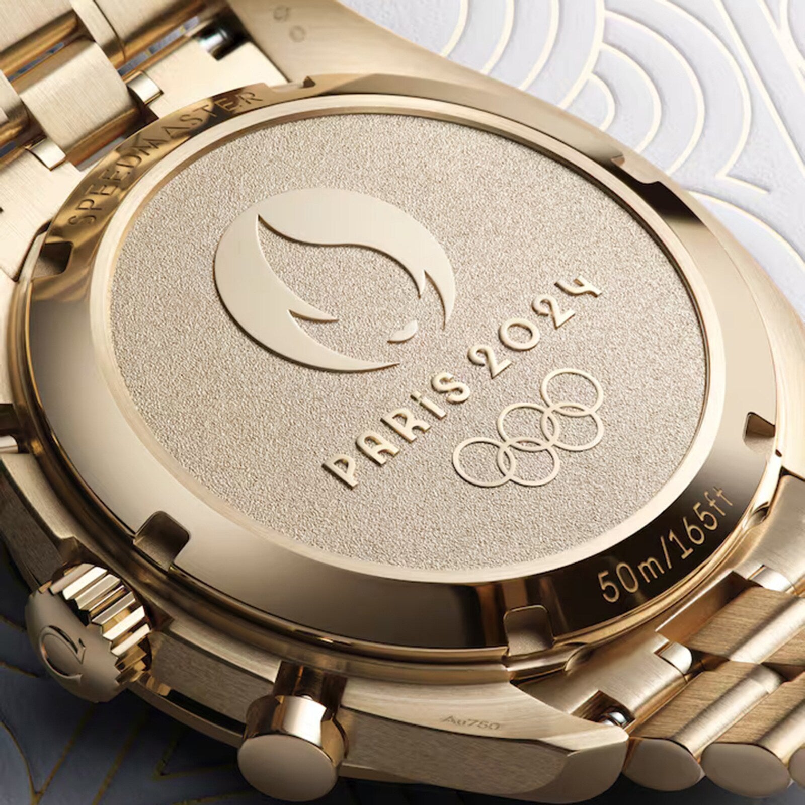 Close-up of the OMEGA Speedmaster Chronoscope Paris 2024 Olympics gold caseback, engraved with the Olympic Games Paris 2024 logo, Olympic rings, Master Chronometer certification, and 50m/165ft.