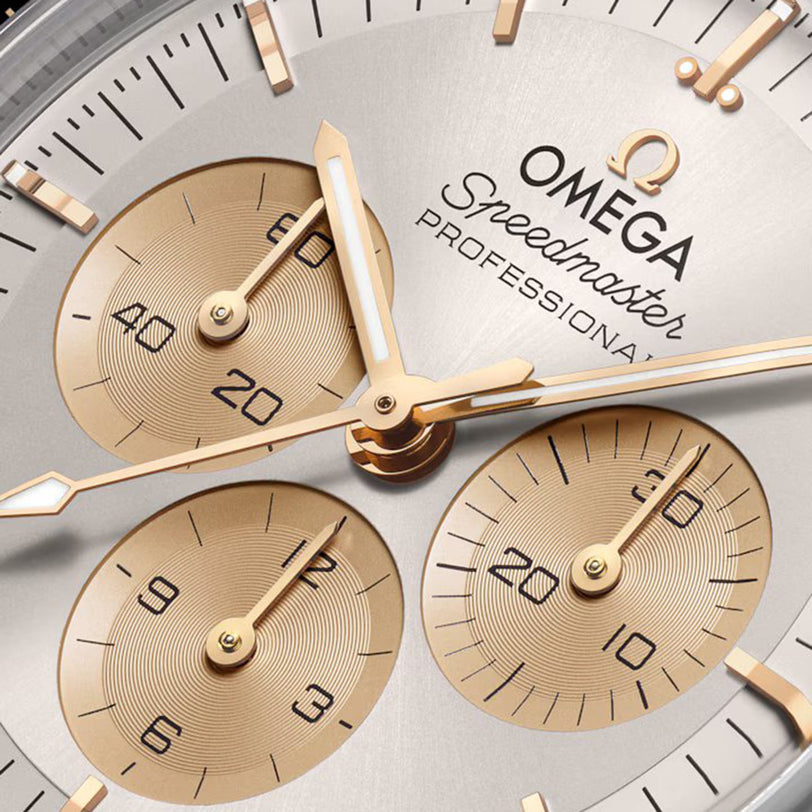 Close-up of the OMEGA Speedmaster Moonwatch Professional Moonshine dial, showcasing three gold subdials, gold hands, and black hour markers on a silver background, driven by the Omega 3861 calibre.