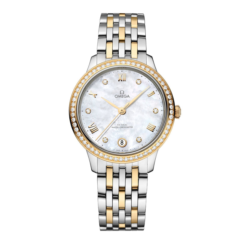 The OMEGA De Ville Prestige features a two-tone design, diamond-set bezel, mother-of-pearl dial, gold Roman numeral markers, and a date display at 6 o’clock.