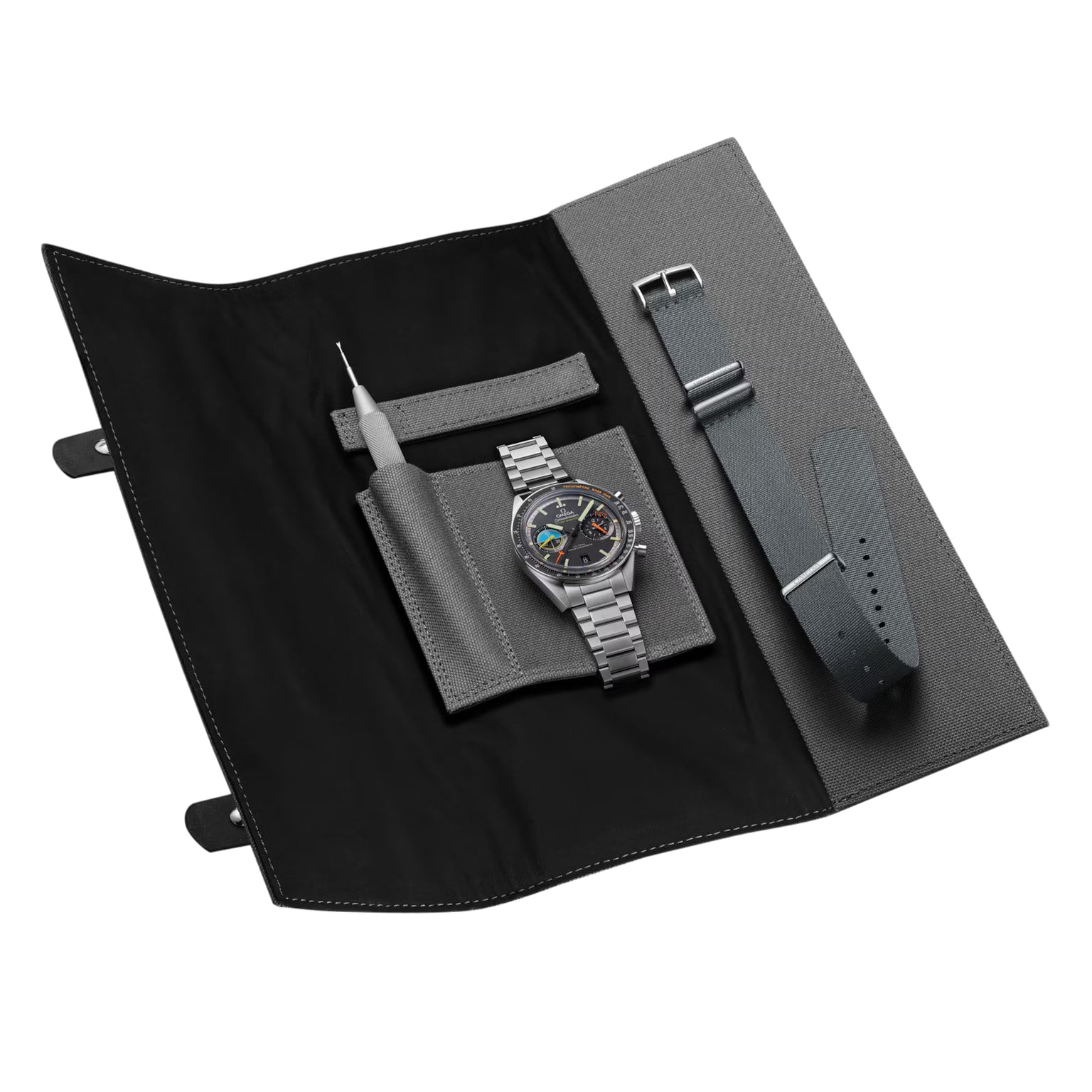 An OMEGA Speedmaster Pilot wristwatch with a stainless steel strap, extra green strap, and tool is displayed on an open gray and black watch roll—celebrating the legacy of Moon landings.