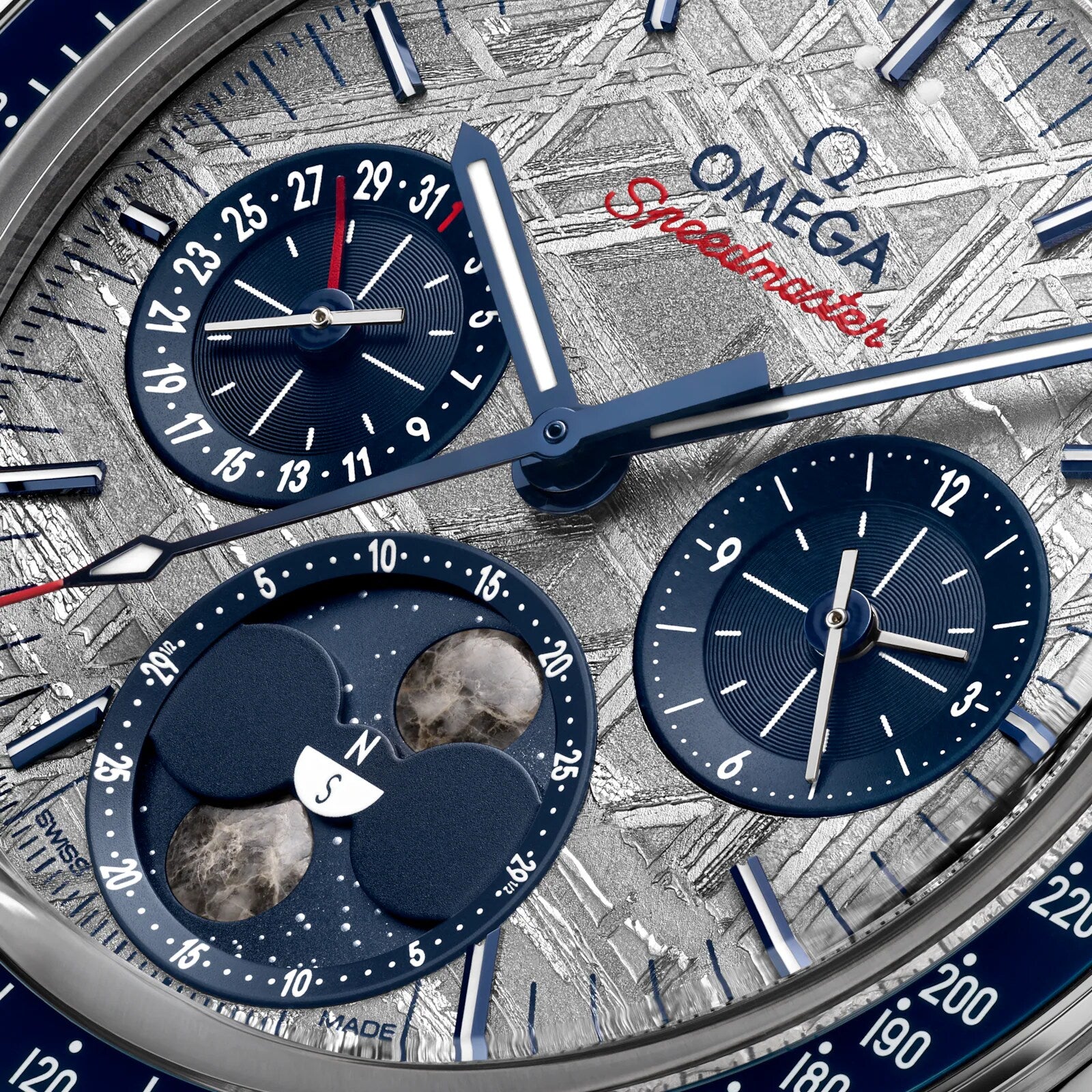 Close-up of the OMEGA Speedmaster Moonphase Meteorite watch face, highlighting chronograph subdials, a date indicator, and moonphase complication set against a textured meteorite dial.