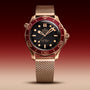 An OMEGA Seamaster Diver 300M with bronze gold case, mesh strap, dark dial, and burgundy bezel, featuring Co-Axial Master Chronometer precision, is shown against a gradient red background.