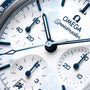 Close-up of an Omega Speedmaster watch face with blue and silver details.