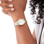 A person with curly hair and manicured nails wears a Longines Flagship wristwatch featuring a silver and gold analog design, diamond indexes, white dial, and date display.