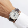 A wrist wearing the Longines Master Collection Chrono Moonphase watch, featuring multiple dials and a stainless steel case, paired with a white dress shirt.