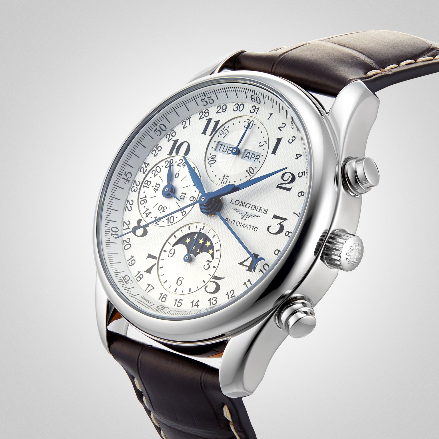 The Longines Master Collection Chrono Moonphase wristwatch features a white dial, blue hands, moonphase chronograph, multiple subdials, date and day displays, leather strap, and polished stainless steel case shown at an angle on a light background.