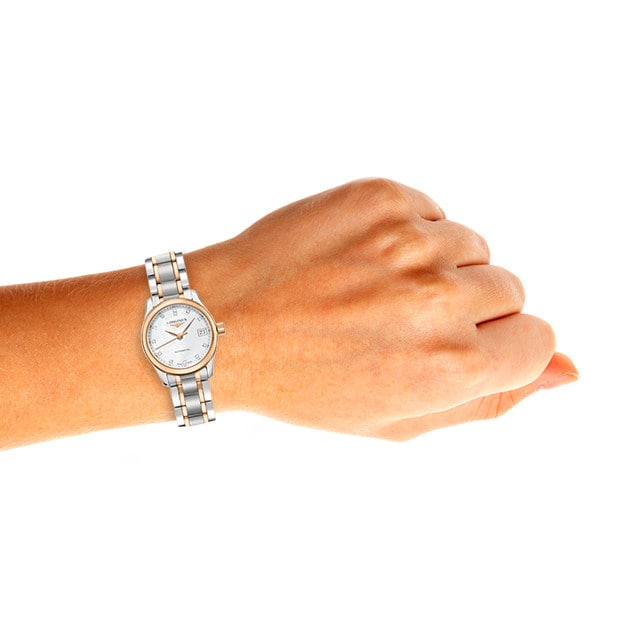 A left hand wears a Longines Master Collection watch with a silver case and mother-of-pearl dial, shown against a plain white background.