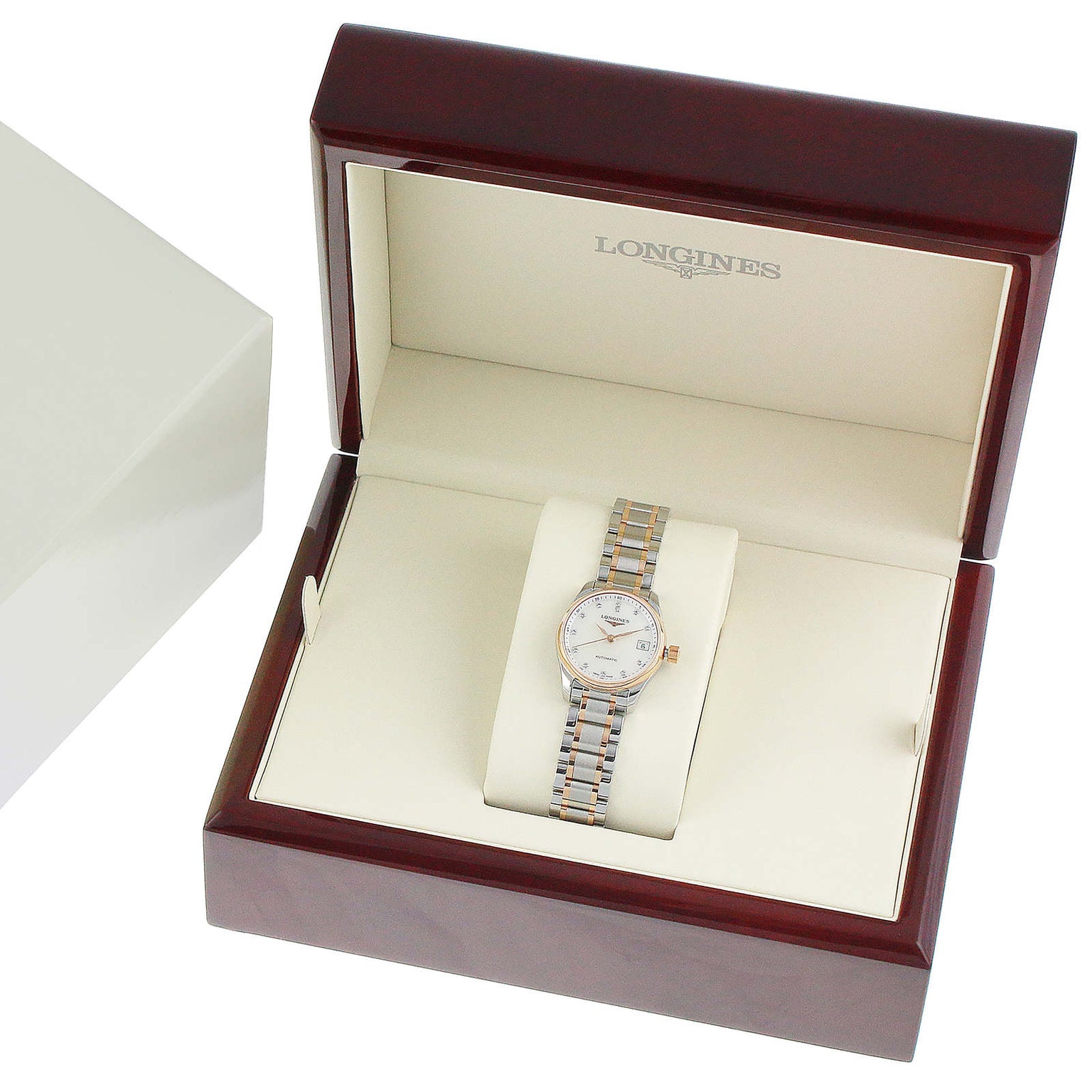 A Longines Master Collection wristwatch with a mother-of-pearl dial and a silver-gold metal band is presented in an open wooden box lined with cream fabric.