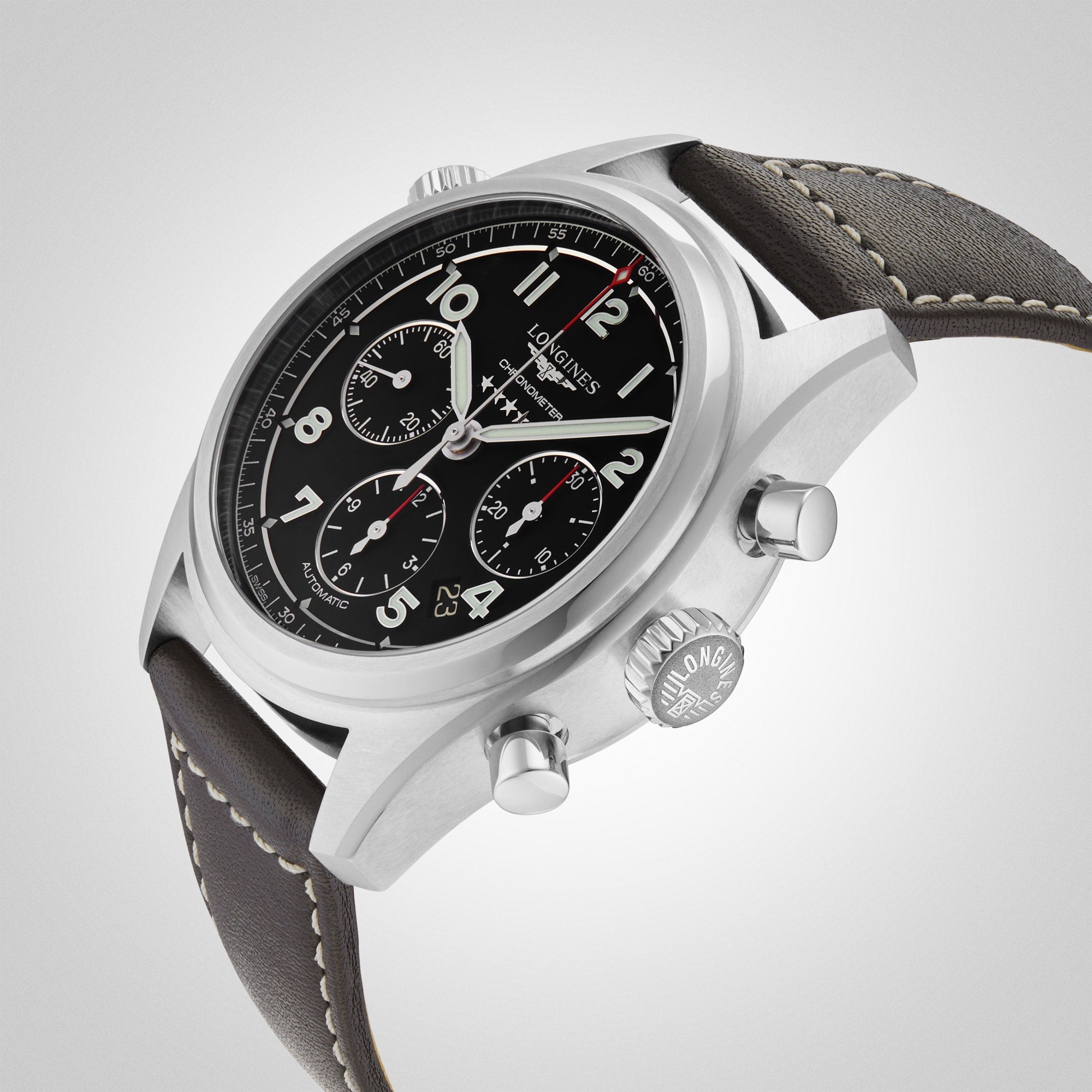 The Longines Spirit Chronograph wristwatch features a black dial with three subdials, grey leather strap, and L688.4 calibre movement, displayed against a light grey background.