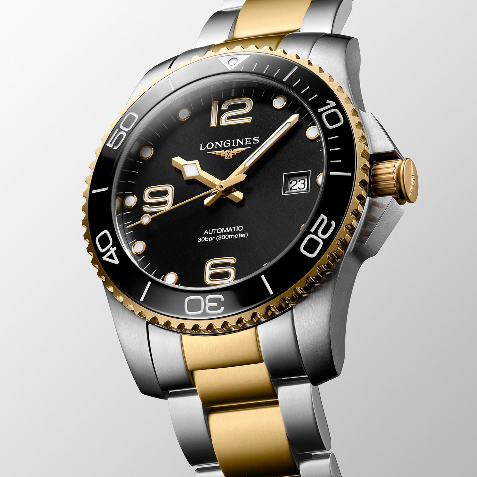 The Longines HydroConquest automatic watch features a black dial, gold bezel, two-tone silver and gold bracelet, date at 3 o’clock, and high water resistance.