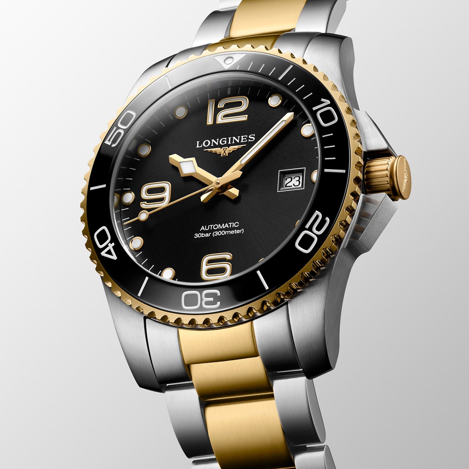 The Longines HydroConquest automatic watch features a black dial, gold bezel, two-tone silver and gold bracelet, date at 3 o’clock, and high water resistance.