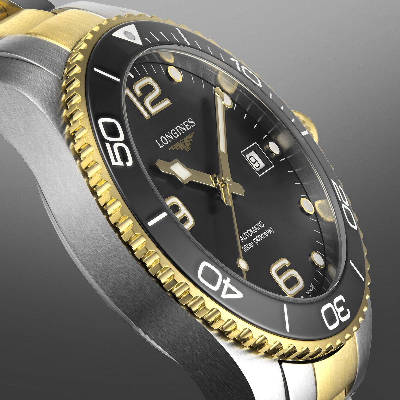 Close-up of a Longines HydroConquest diving watch featuring a black dial, gold and silver bezel, luminous hands, and date display set to the 9th.