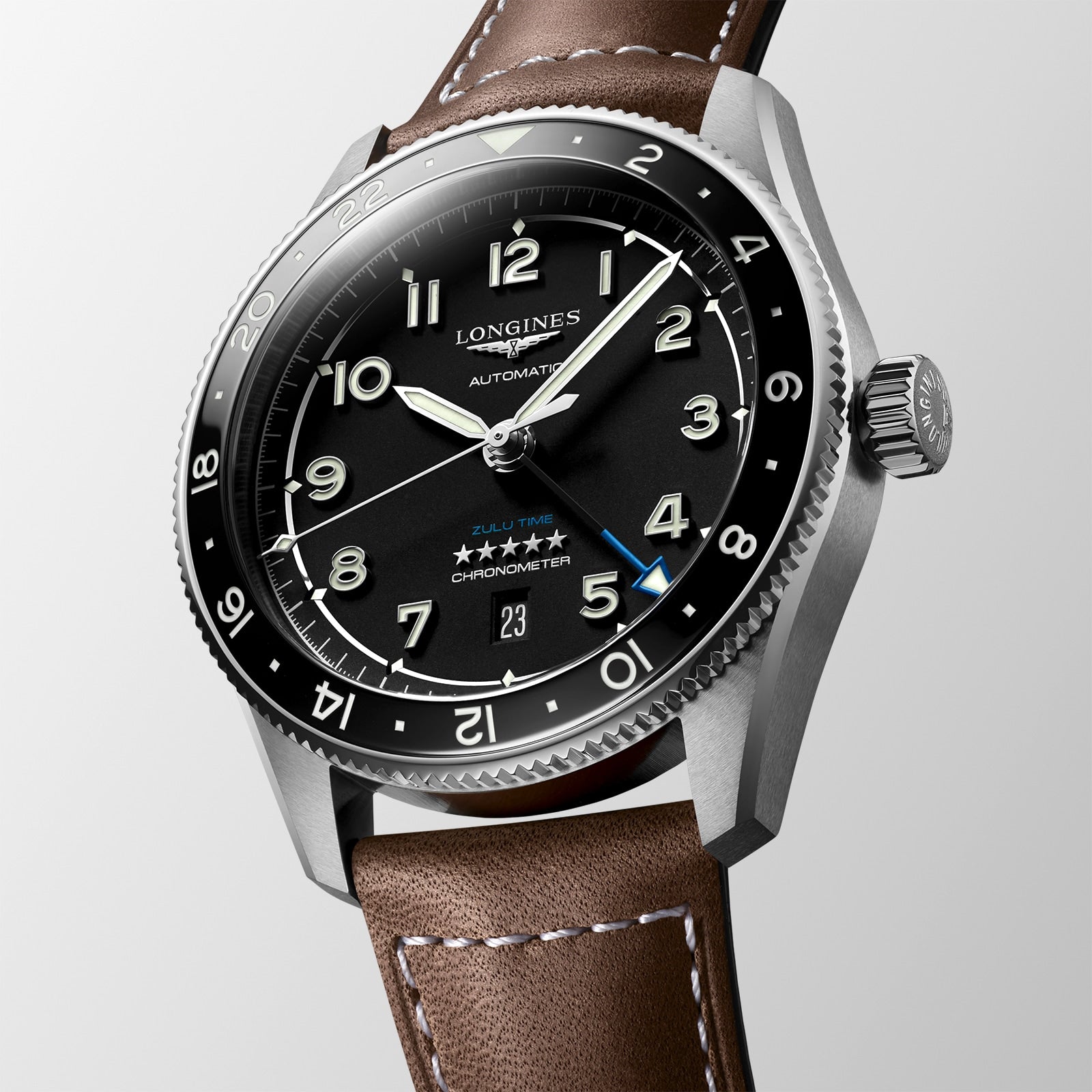 The Longines Spirit Zulu Time automatic watch features a black dial with white numerals, a stainless steel case, brown leather strap, and date display at 6 o’clock.