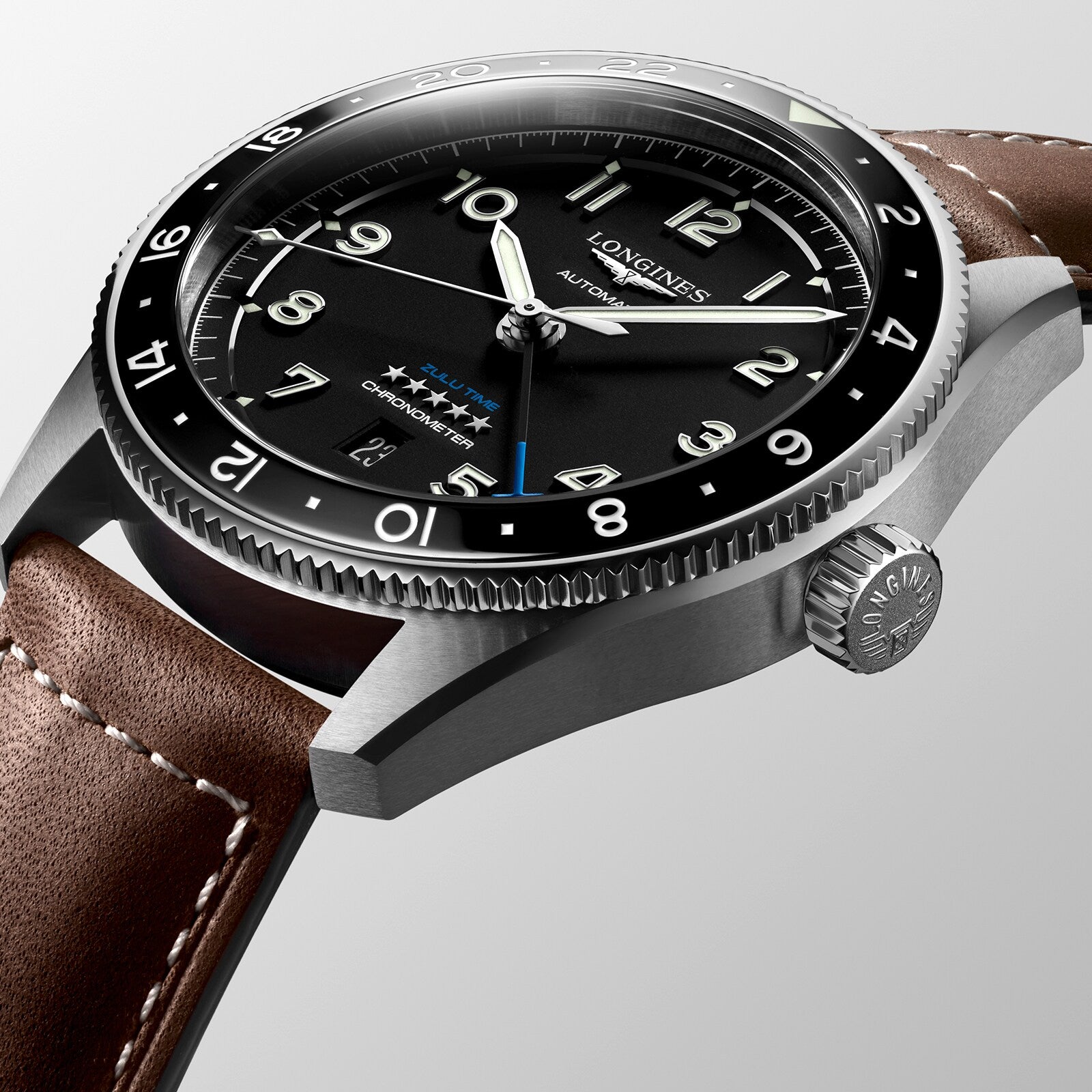 Close-up of the Longines Spirit Zulu Time automatic watch featuring a stainless steel case, black dial, silver hands, date window, brown leather strap, and textured crown.