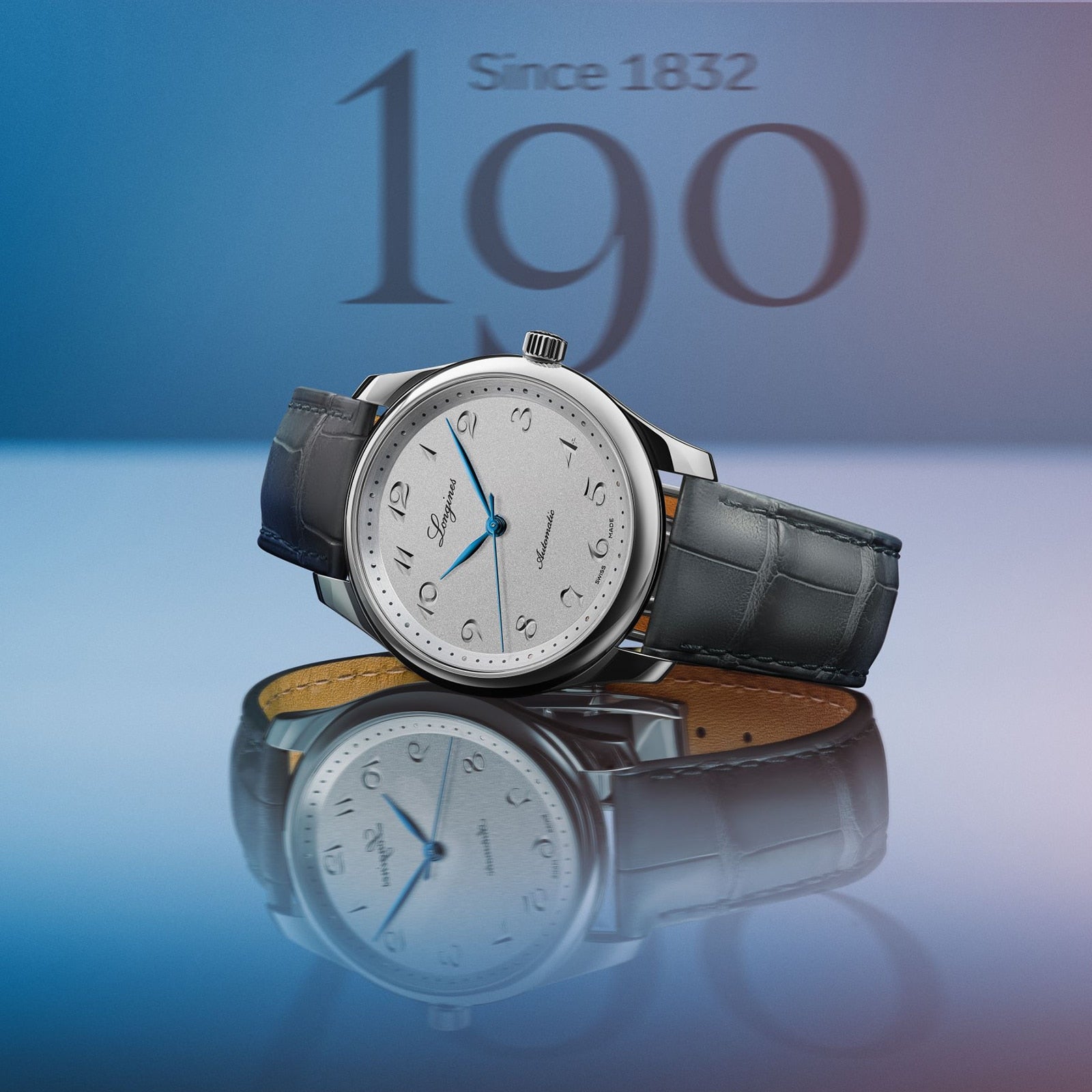 A Longines Master Collection luxury wristwatch with a blue leather strap and silver dial is showcased against a blue background, featuring Since 1832 and bold 190 text behind it to highlight its exclusivity.