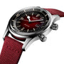 A close-up of the Longines Legend Diver watch, featuring a burgundy gradient dial, silver hands, date window, and a textured red fabric strap.