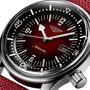 Close-up of the Longines Legend Diver watch featuring a red dial, black bezel, white markers, date window at 3 o’clock, and a red fabric strap.