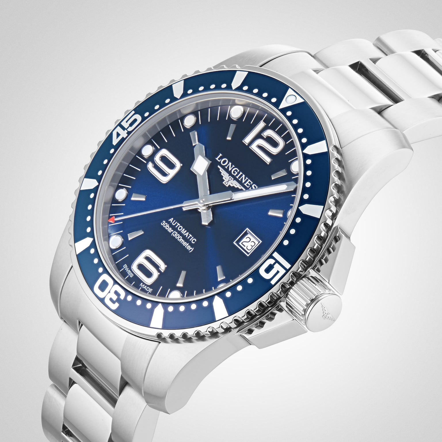 The Longines HydroConquest features a stainless steel case, blue dial and bezel, silver hour markers, automatic movement, and date display at 3 o’clock, shown against a white background.