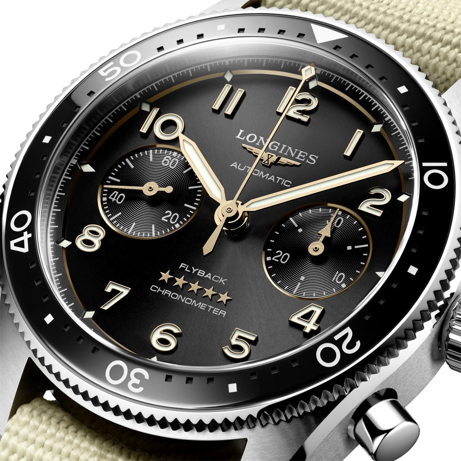 Close-up of a Longines Spirit Flyback wristwatch, featuring a black dial, gold-tone hands, calibre L791 automatic chronometer movement, and a beige fabric strap.