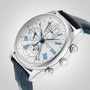 The Longines Master Collection Chrono Moonphase features a silver case, white dial with blue Roman numerals, three chronograph subdials, two pushers, and a blue leather strap, shown against a plain gray background.