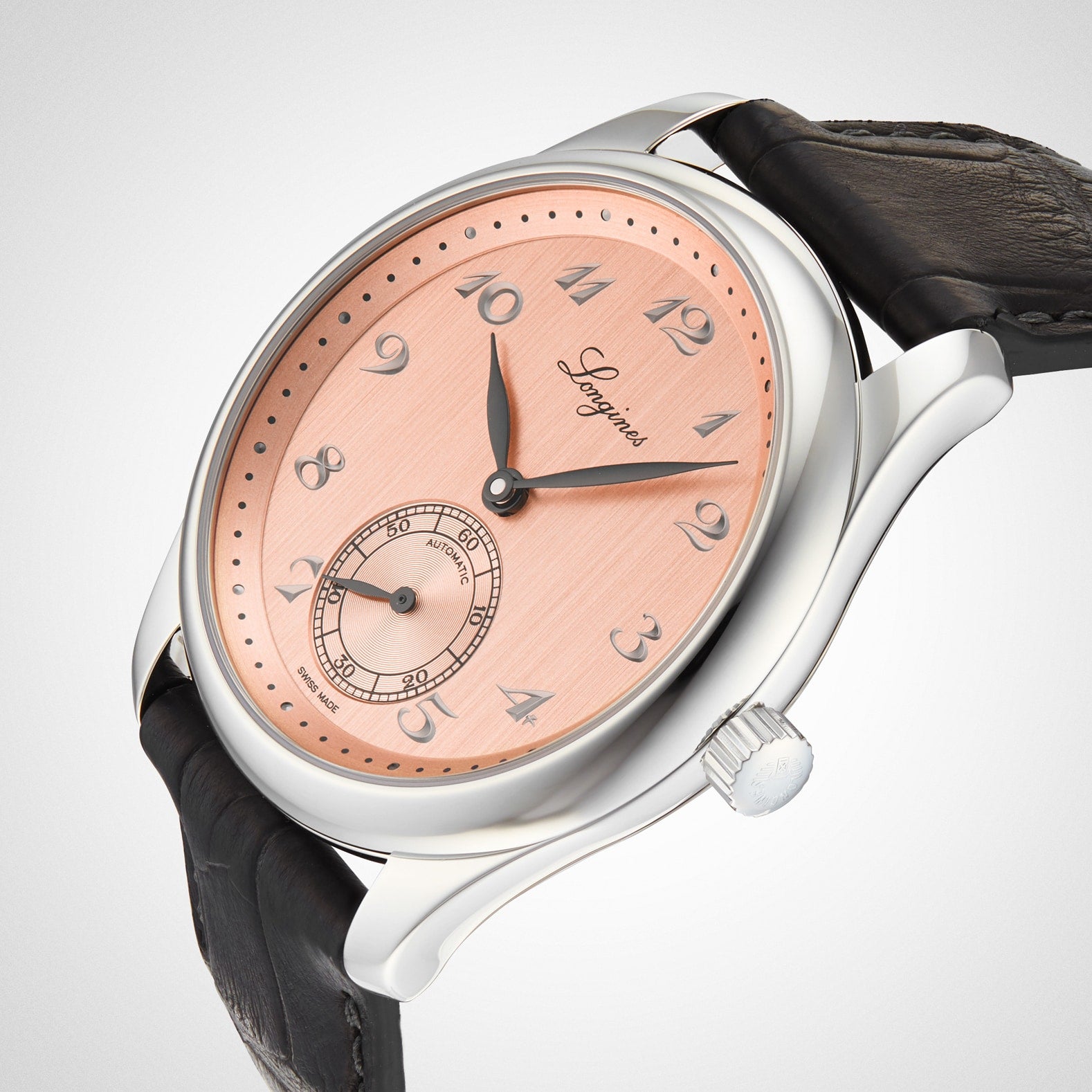 The Longines Master Collection wristwatch features a salmon pink dial with Arabic numerals, small seconds at 6 o’clock, self-winding movement, silver case, and black leather strap.