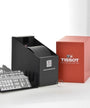The Tissot Le Locle Powermatic 80 watch box set includes a red box, black organizer, informational inserts, and a transparent watch holder, all inspired by the Swiss Jura Mountains and displayed on a white background.