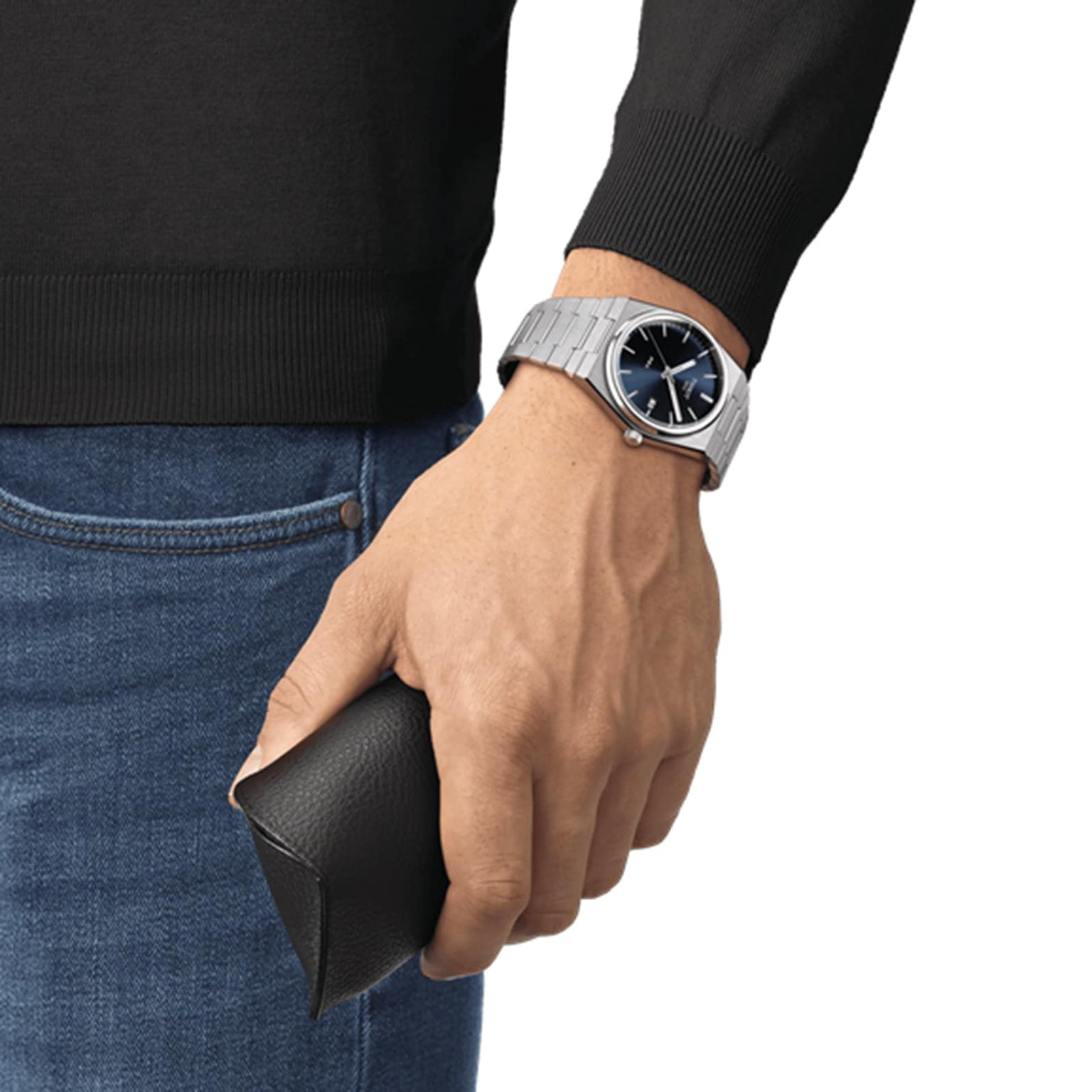 Wrist wearing the Tissot PRX holding a small leather case