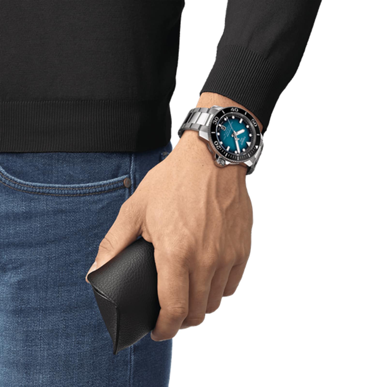 A person wearing a Tissot Seastar 2000 Professional Powermatic 80 watch with a blue dial holds a black textured glasses case.