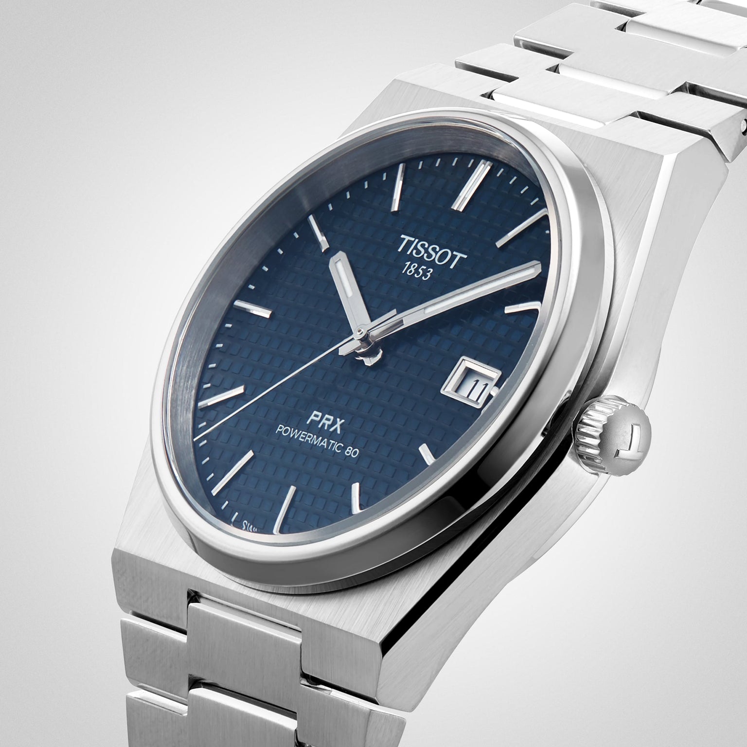 The Tissot PRX Powermatic 80 is a stainless steel wristwatch with a blue textured dial, silver hour markers, date window at 3 o’clock, and advanced Powermatic 80 movement for luxury and precision.