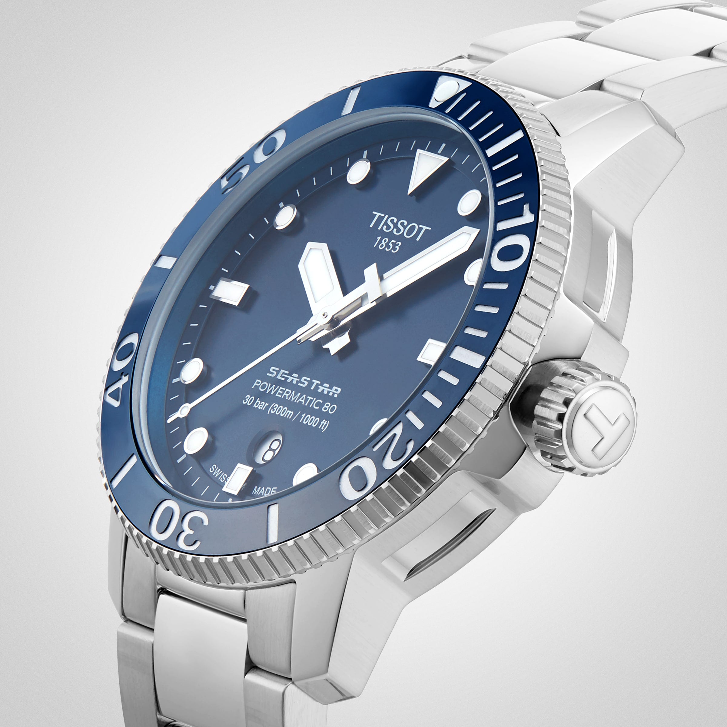 The Tissot Seastar 1000 Powermatic 80 dive watch features a silver stainless steel bracelet, blue bezel and dial, luminous hands and markers, a prominent crown, and the robust Powermatic 80 movement.