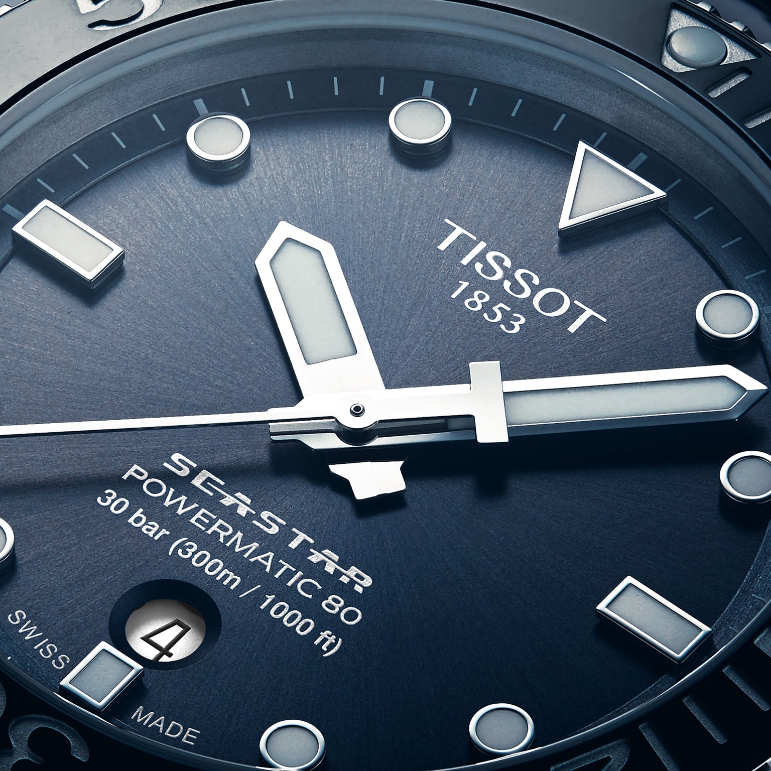 Close-up of the Tissot Seastar 1000 Powermatic 80 divers watch face, showing hands, date window, and inscriptions on a textured blue dial.