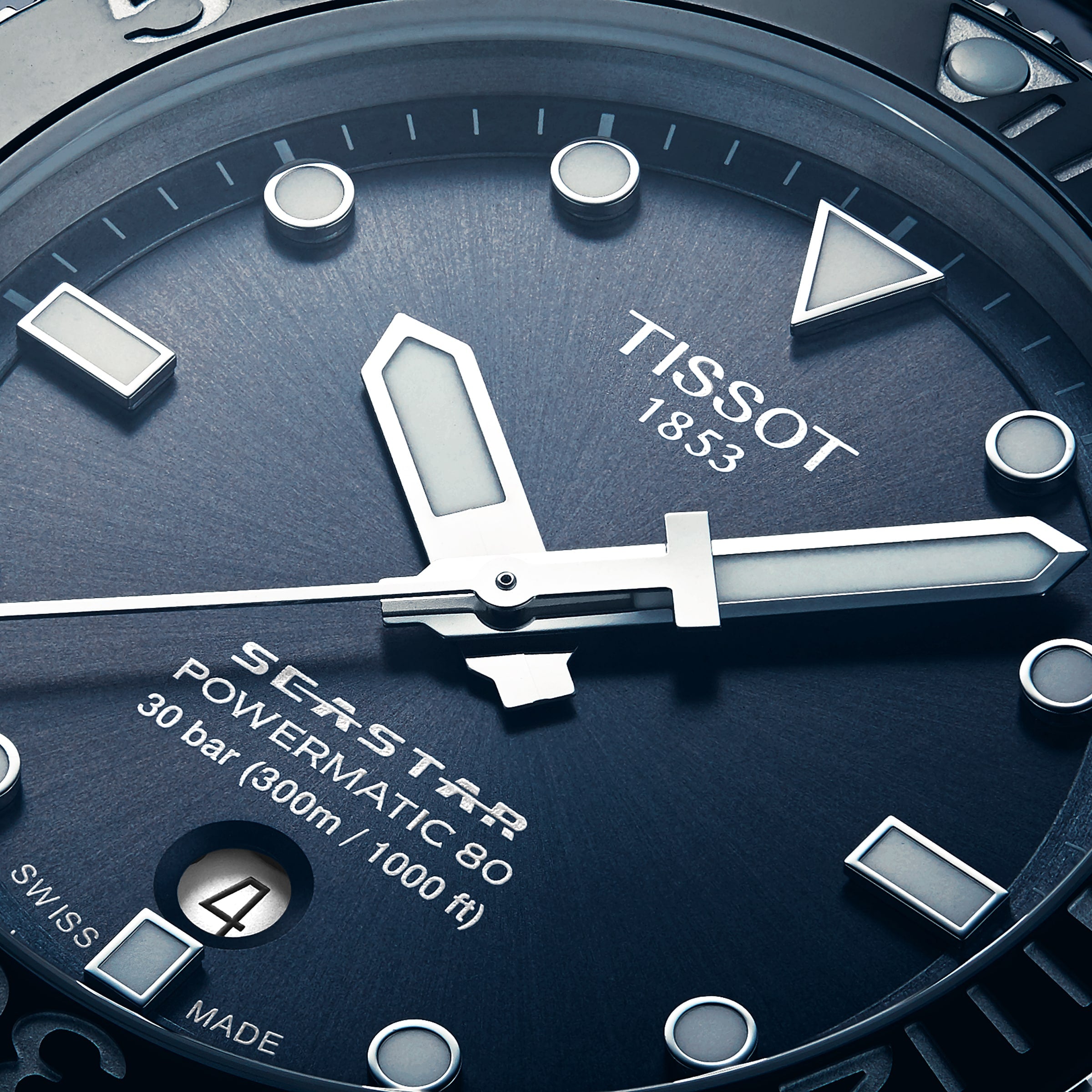 Close-up of the Tissot Seastar 1000 Powermatic 80 divers watch face, showing hands, date window, and inscriptions on a textured blue dial.