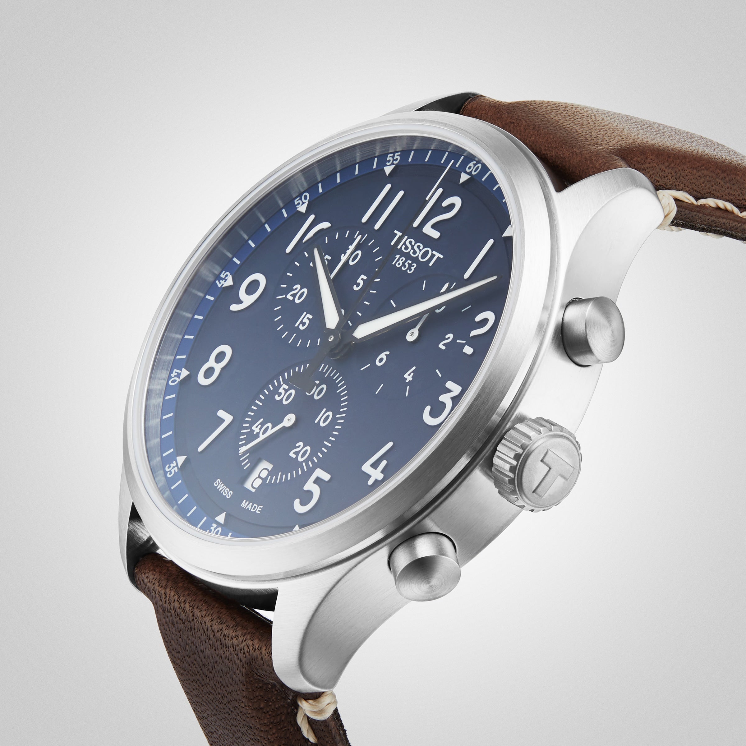 The Tissot Chrono XL Vintage features a blue dial with white numerals, chronograph subdials, a stainless steel case, and a brown leather strap, combining vintage-inspired style with modern elegance.