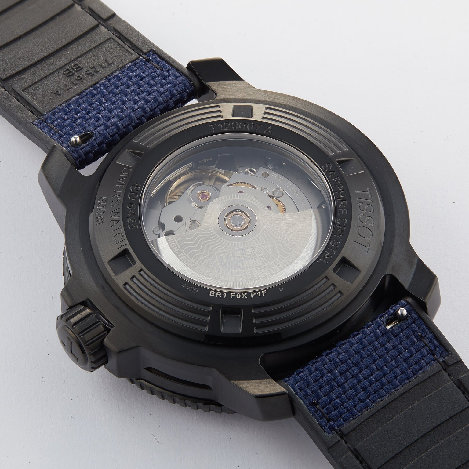 Close-up of the back of the Tissot Seastar 2000 Professional Powermatic 80, showing its automatic Powermatic 80 movement through a transparent case back, with a blue fabric and black rubber strap.