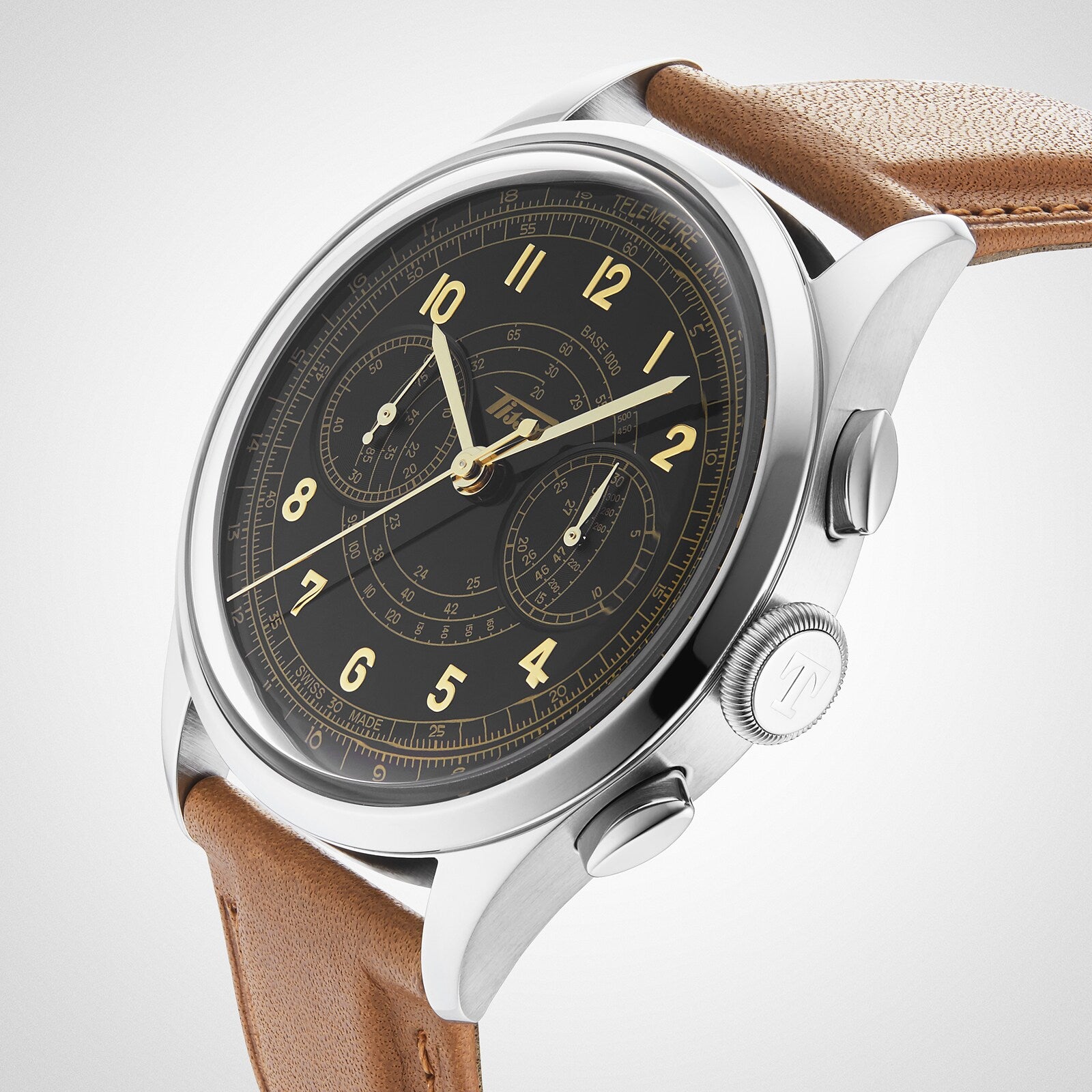 The Tissot Telemeter 1938 features a stainless steel case, black dial with gold numerals, two subdials, and a light brown leather strap, powered by Swiss automatic movement.